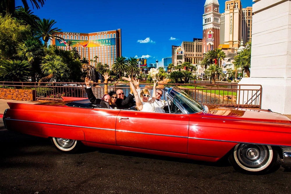 Jennifer and Mike Attisano and others in a red convertible with Las Vegas skyline in background