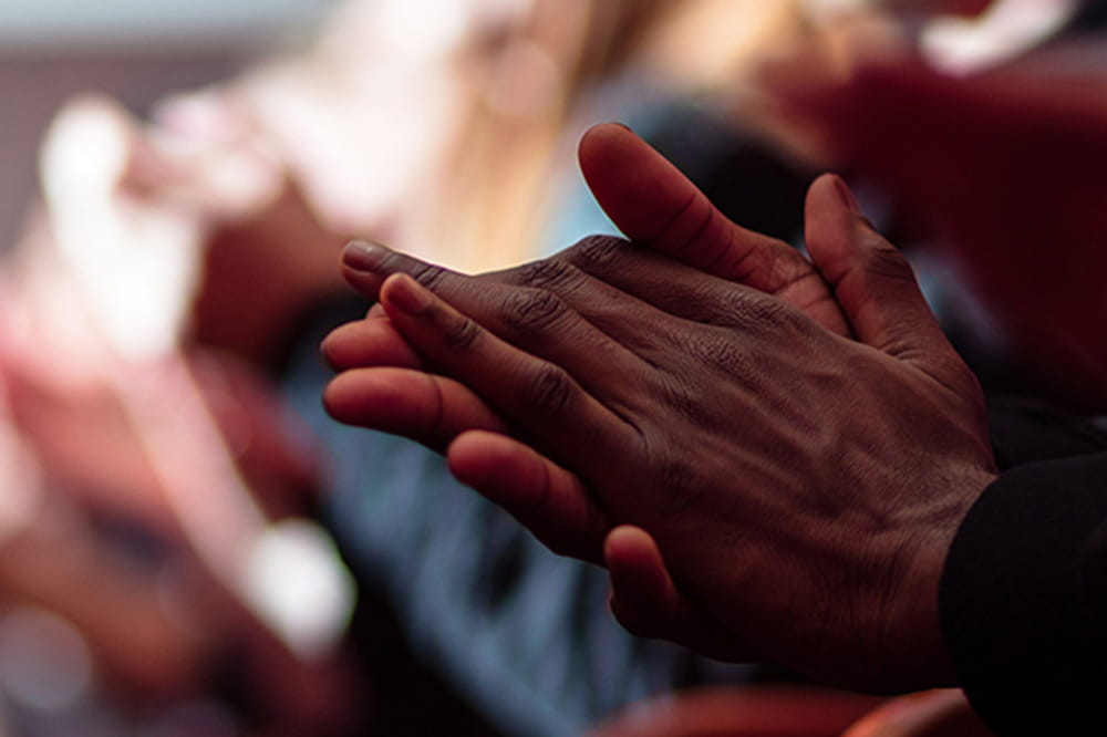 closeup of African American's hands clapping in crowd of people