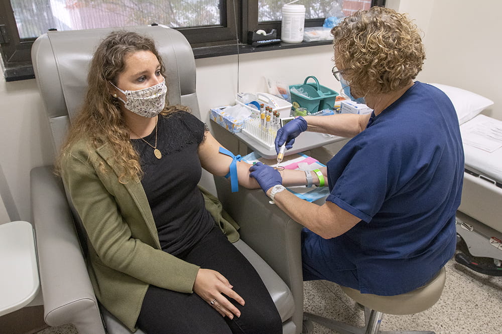 Nurse Cheryl Bath draws blood from Kelly Warren for COVID vaccine clinical trial.