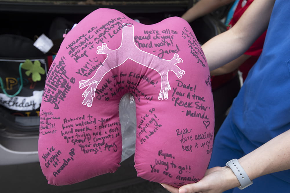 a closeup of a pillow shaped like a set of lungs, signed by team members in black Sharpie