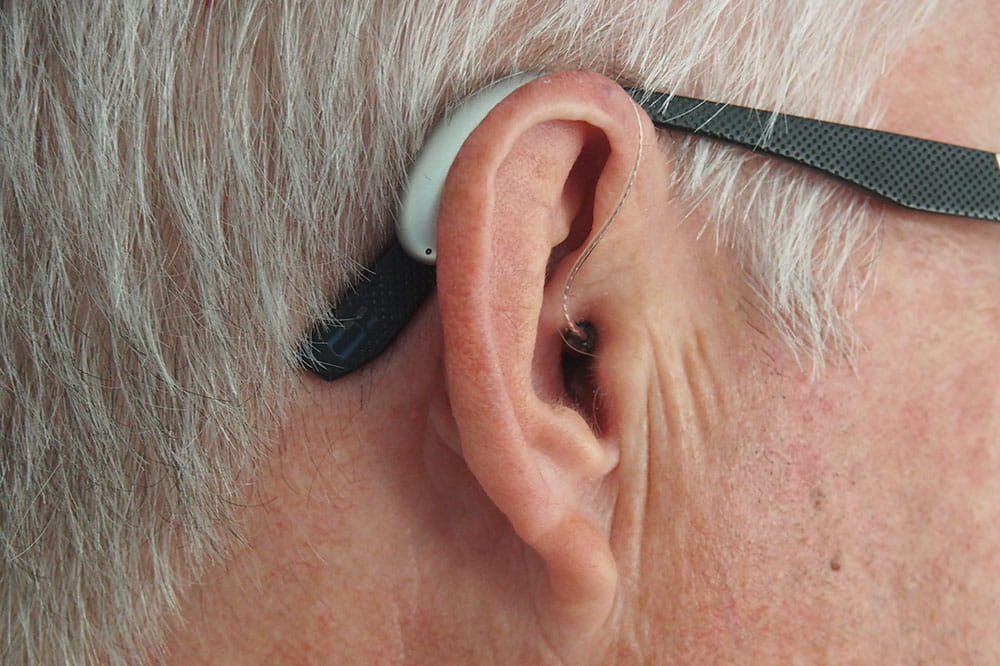 Closeup of a man's ear. He is wearing a hearing aid.