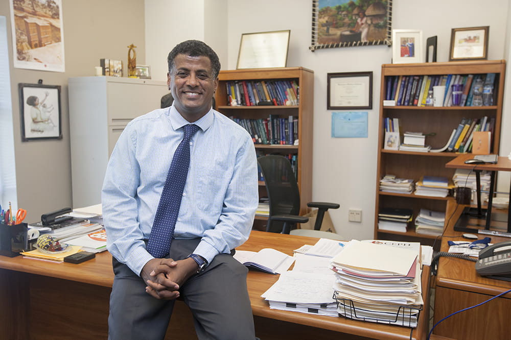 Dr. Gebregziabher sitting on desk.