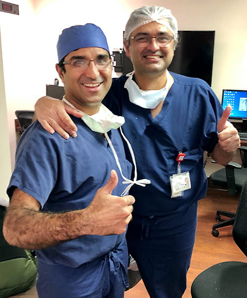 two surgeons give a thumbs up smiling broadly