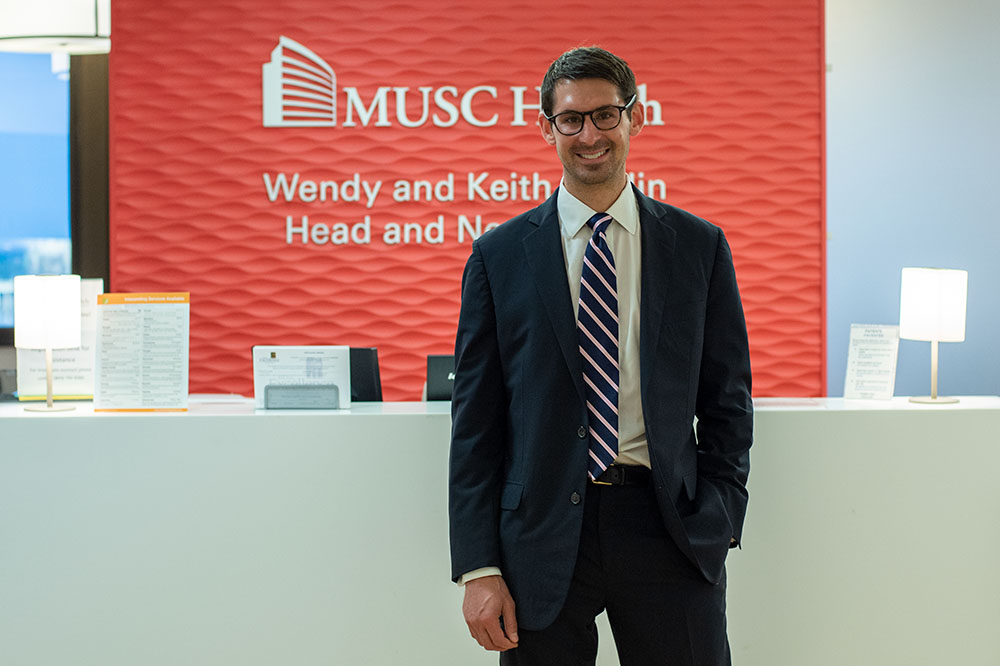 Dr. Evan Graboyes stands in front of Wellin Head and Neck Clinic sign