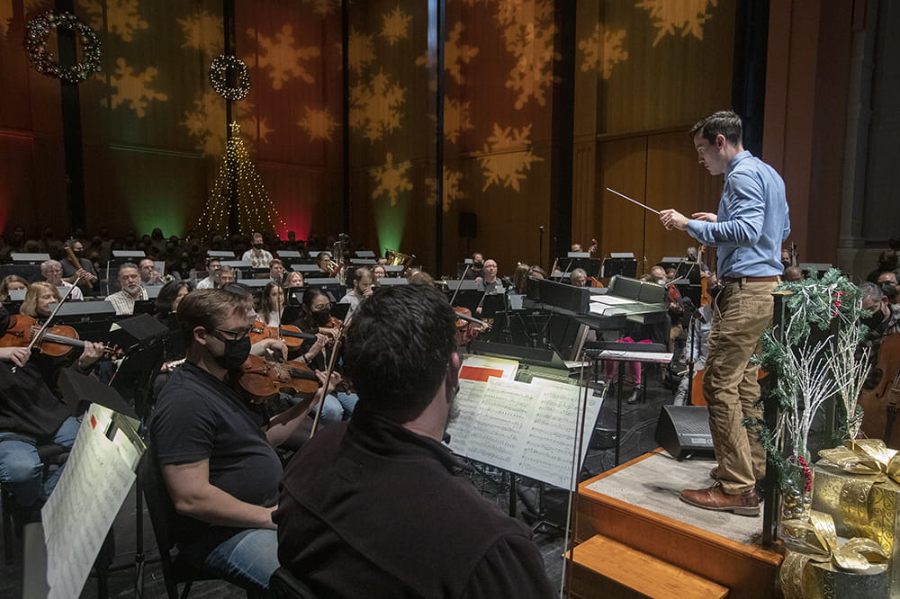 a man stands in front of an orchestra ready to conduct