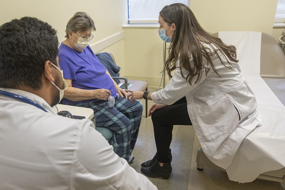 College of Medicine Student Henry Colorado observes as Dr. Colleen Donahue examines patient Sheila Kirby.