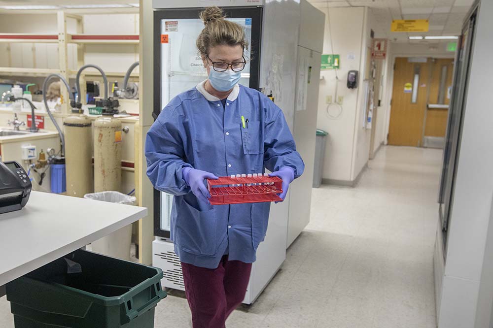 Betsy McLaughlin carries samples to be run through machines to test for covid.