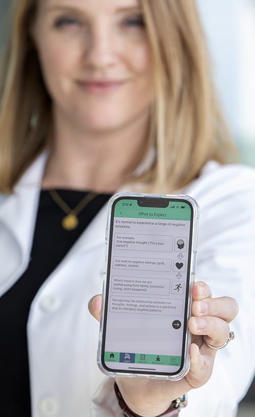 a woman holds a cell phone up to the camera to show what's on the screen, an app that shows how emotions can lead to actions