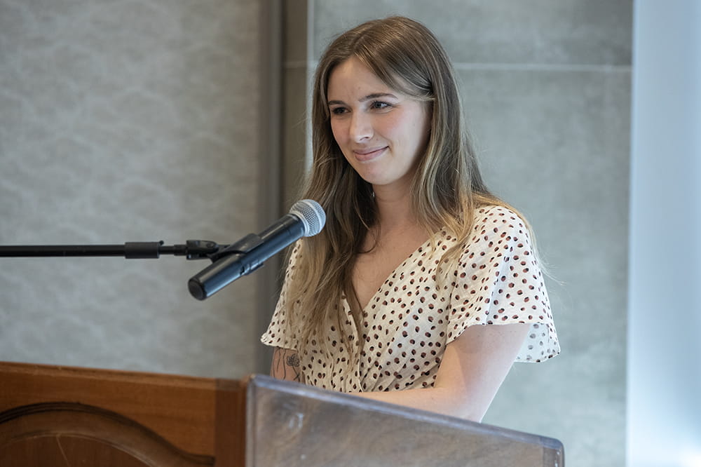 a young woman smiles in a quiet way at a microphone