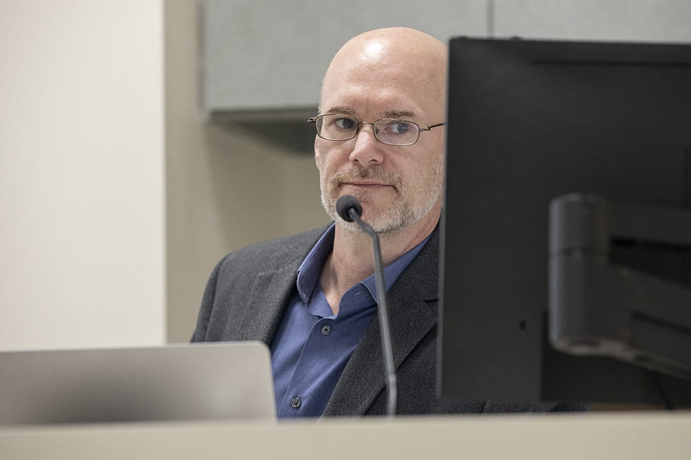 Hamilton Baker looks at his computer monitor as he hosts a discussion on AI in health care