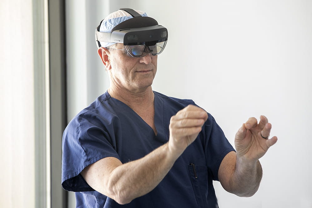 Dr. Katz stands in a room, wearing a VR headset and a pair of scrubs. His hands are out in front of him like he's conducting an orchestra