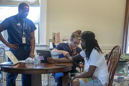 A female medical students takes the vitals of a homeless man at MUSC's Telehealth clinic