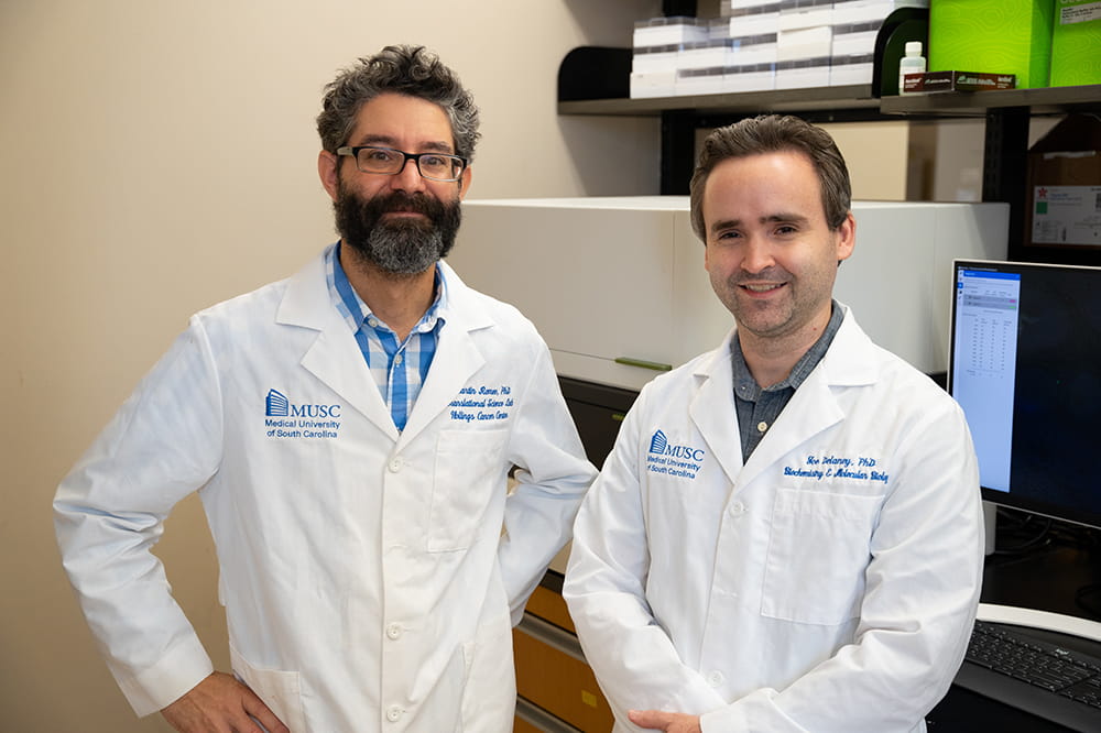 two men in white lab coats pose