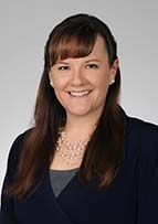 Headshot of Dr. Kristy Brittain. She has long reddish hair and is wearing a necklace and jacket.