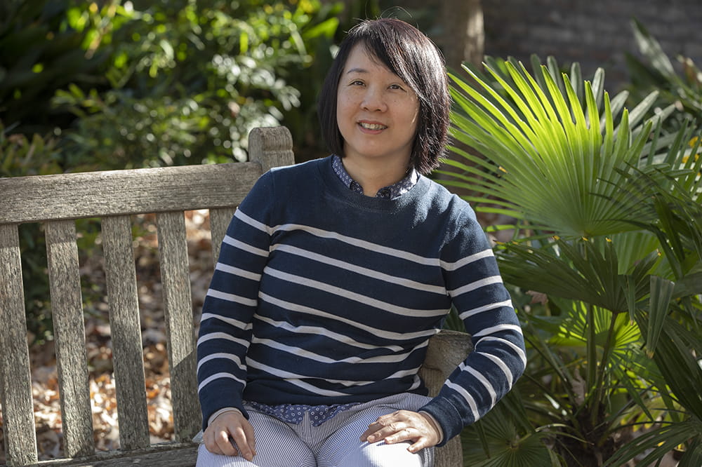 Dr. Wei Jiang seated on a bench outside.