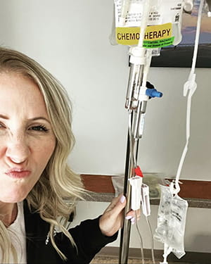 a woman makes a face at the camera as she sits in a chemo infusion chair