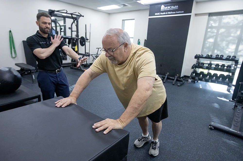 One man coaches another, who is doing a modified form of pushups.