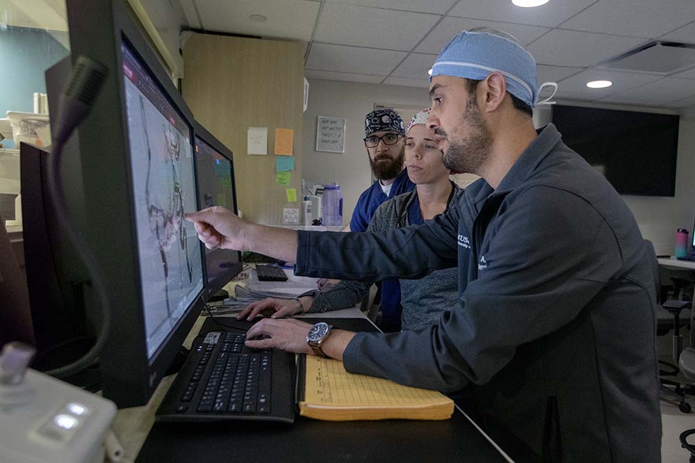 People in medical scrubs look at a computer screen showing a brain scan.