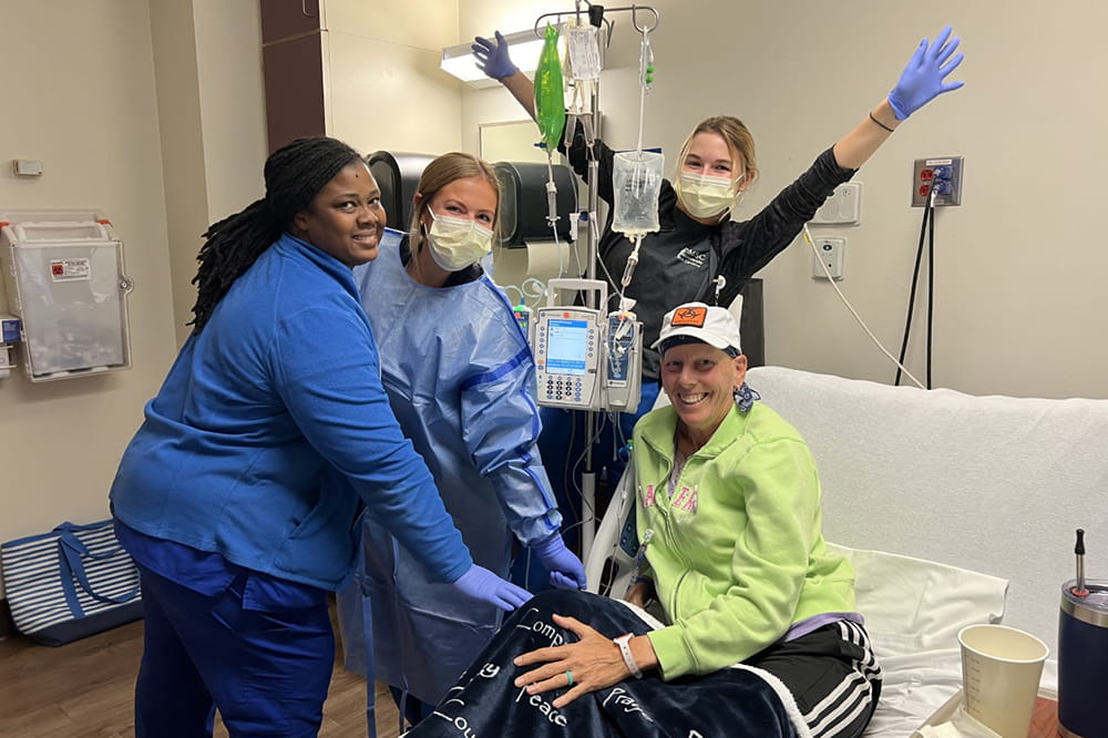 nursing staff cheer behind a patient's bed