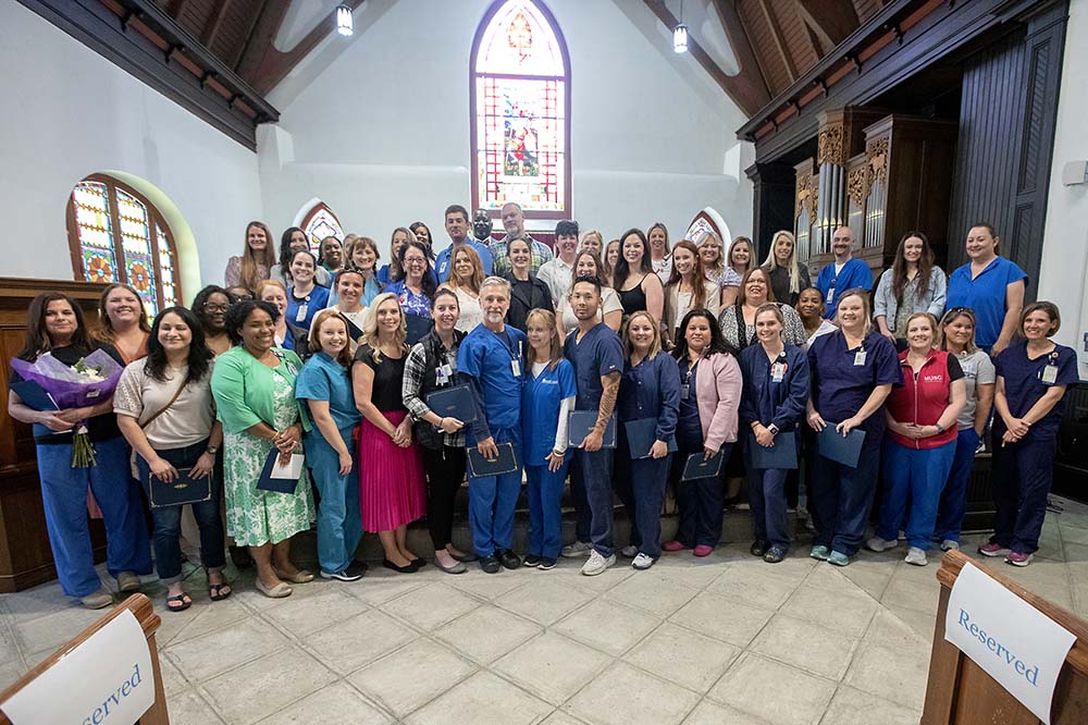 Large group of nurses gathered at front of a church smiling.