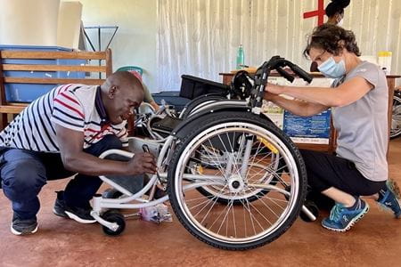 A man and a woman work on assembling a wheelchair