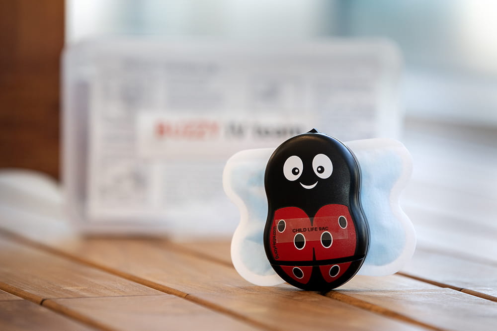 A small black and red plastic ladybug device with a small ice pack attached