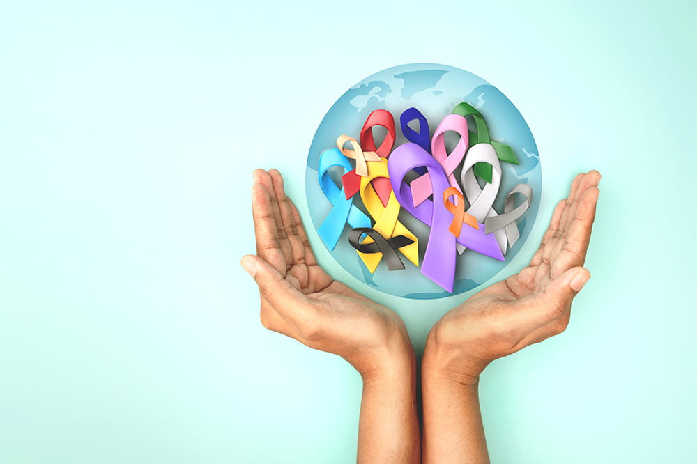 image of colorful awareness ribbons superimposed over globe with hands holding them up