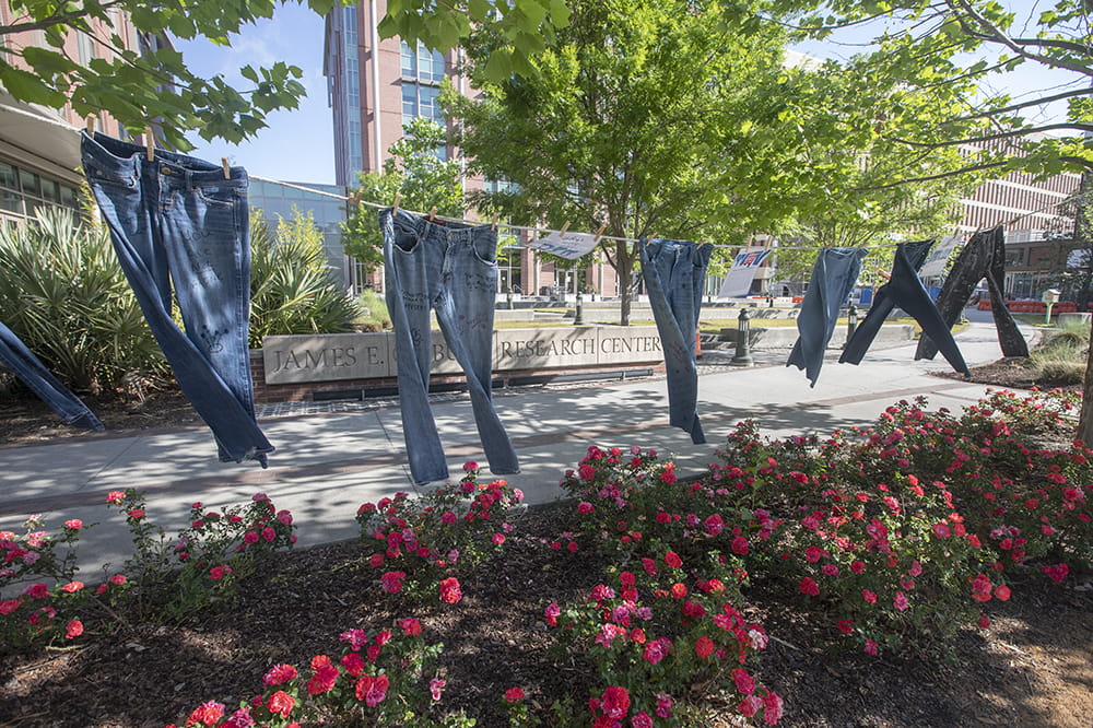 Six pairs of jeans hang from a clothes line.