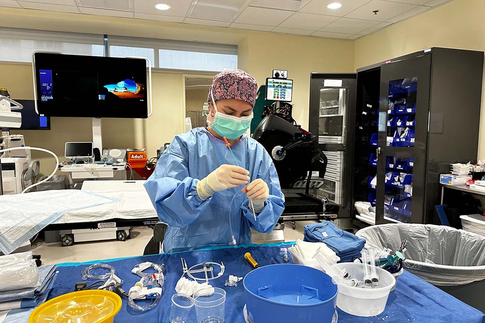 Invasive cardiovascular technology student Kit Kicinski wears scrubs as she works in a lab.