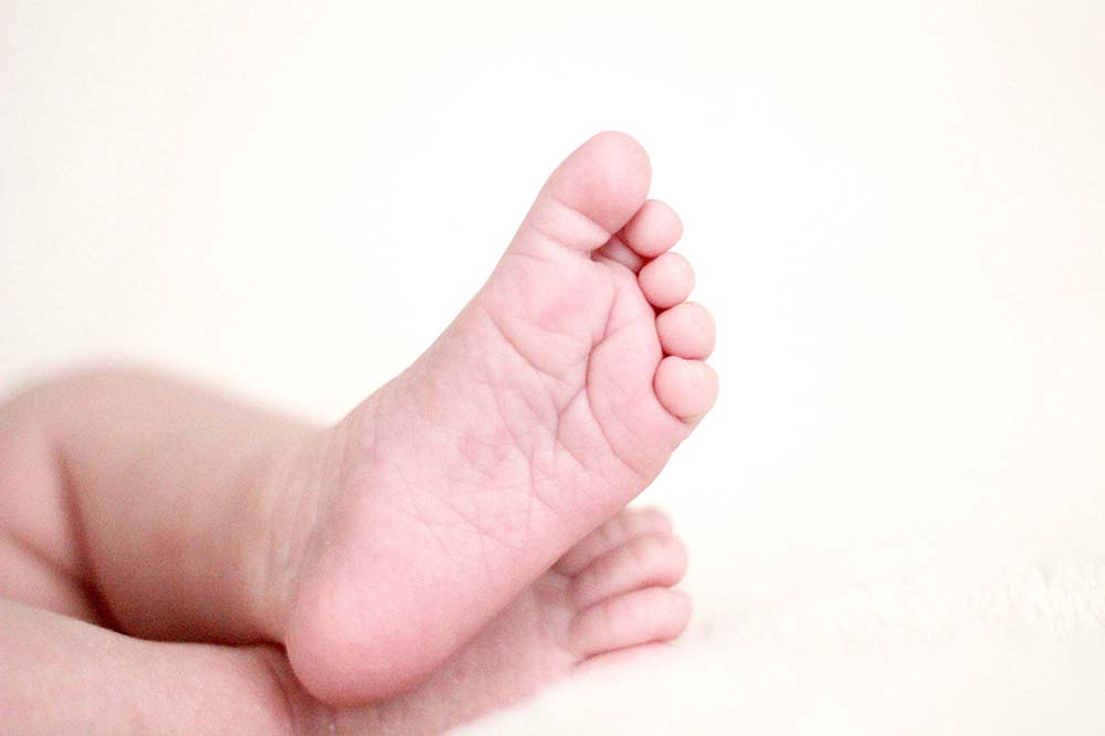 small baby feet crossed on a white background