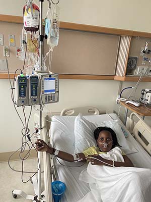 A boy lies in a hospital bed receiving a transfusion.