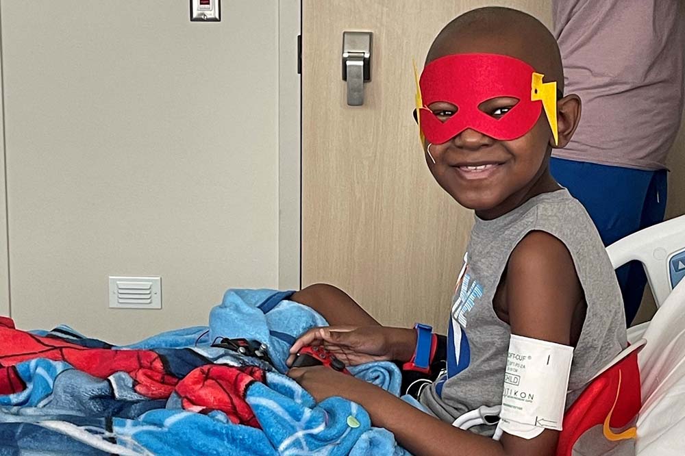 Kaycen Martin in a hospital bed wearing a superhero mask