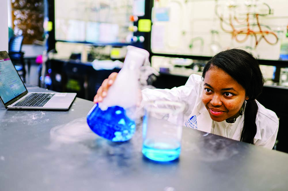 Young woman with long braid hanging over her shoulder looks at laboratory equipment.