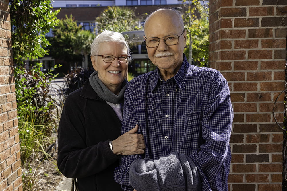 an older couple poses under a brick pergola