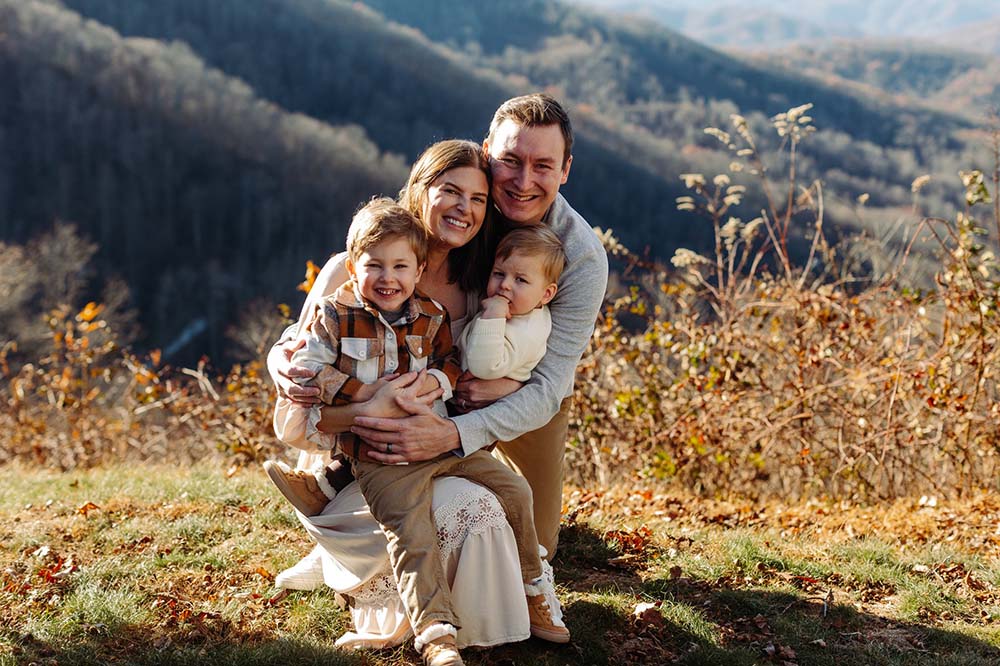 A man and a woman hold two boys in an outdoor setting.