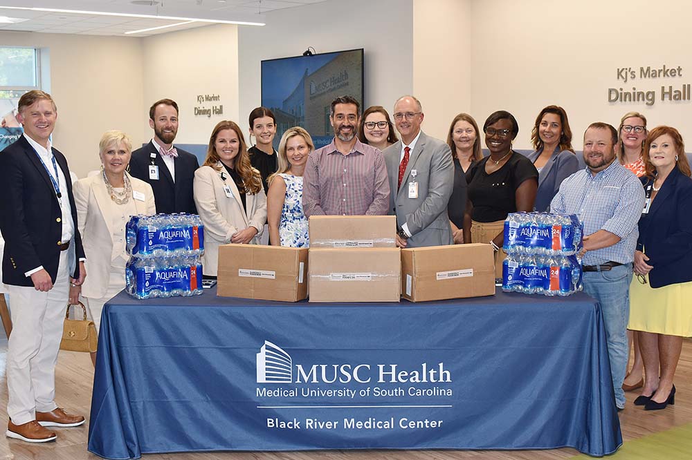 Group of MUSC employees standing around a table with boxes on it. 