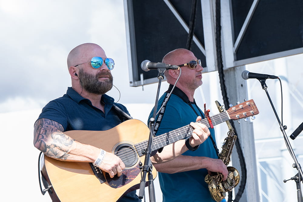 two men stand on stage playing instruments