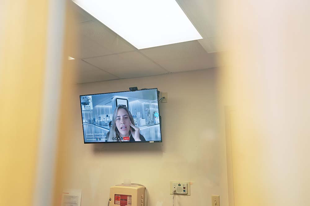 A computer monitor on a wall shows the face of a woman.