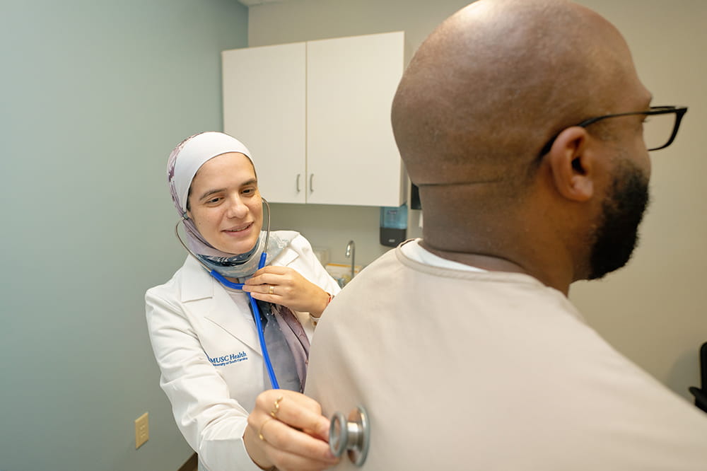 Doctor placing a stethoscope on a patient's back.