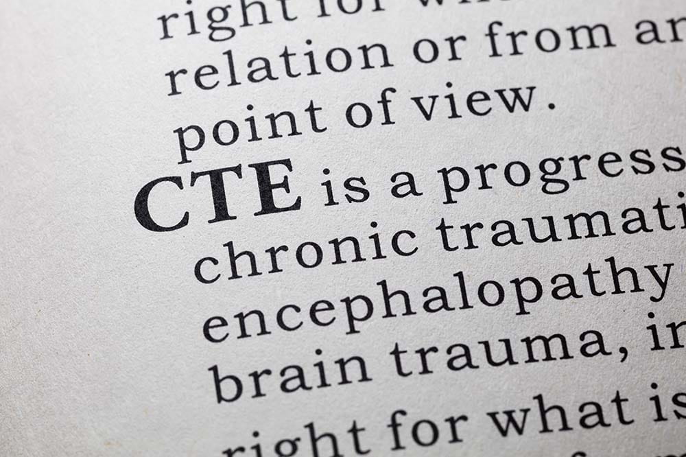 An illustration of a dictionary page with the words CTE is a progress...chronic traumatic...encephalopathy...brain trauma